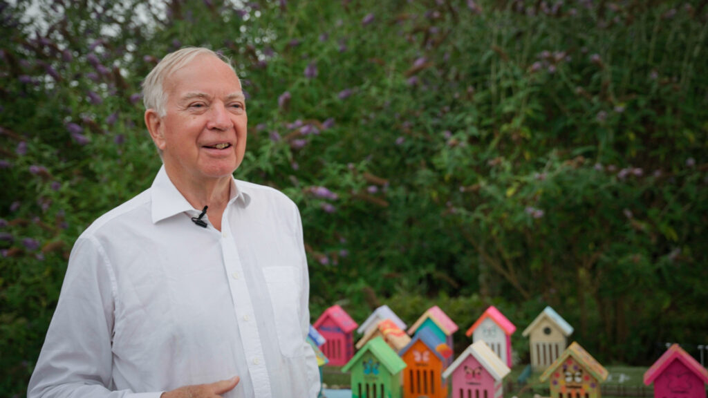 Image of Hugh Ellerton trustee of Butterfly Conservation and some colourful butterfly houses in the background.